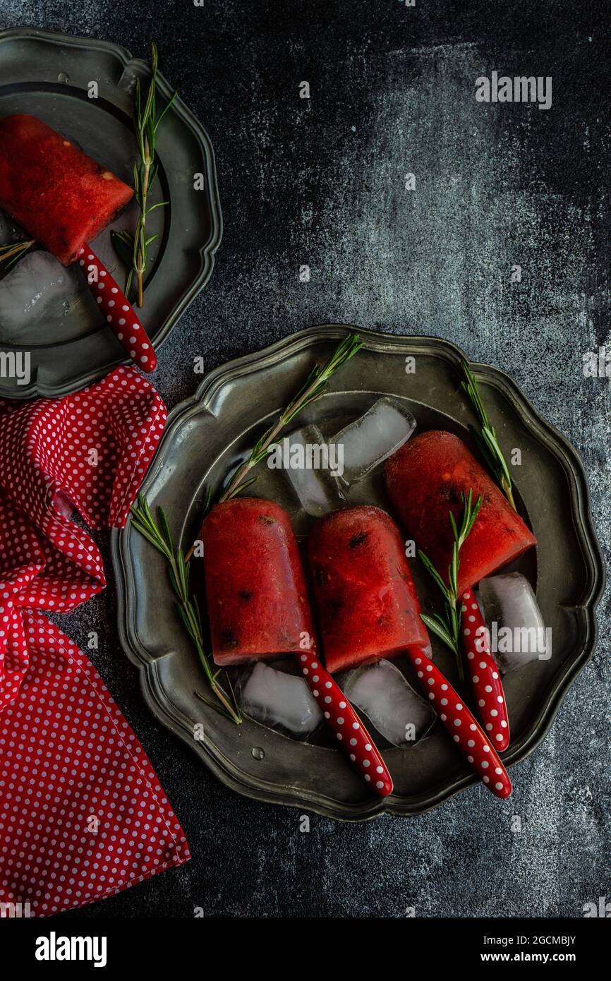 Wassermelonen-Eis auf einem Teller mit Eiswürfeln und Rosmarin Stockfoto