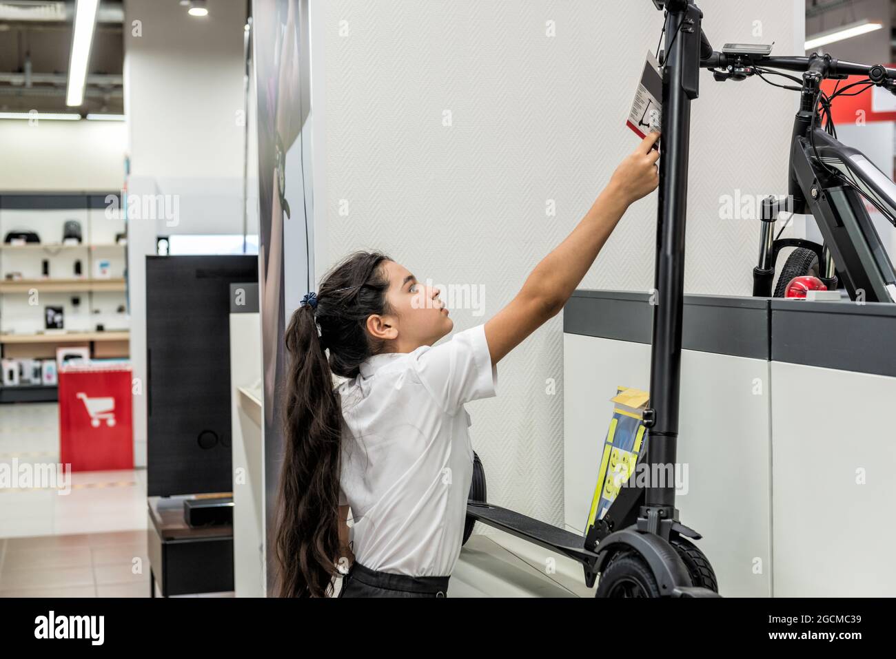 Ein Teenager-Mädchen in einem Geschäft studiert einen Anhänger auf einem Elektroroller Stockfoto