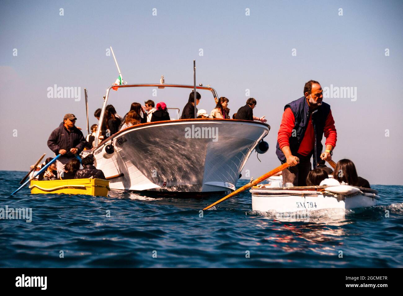 Italienische Ruderer führen Touristen durch einen schmalen Eingang zur natürlichen Meereshöhle auf Capri in die Blaue Grotte, die von den Gästen flach auf dem Rücken liegt. Stockfoto