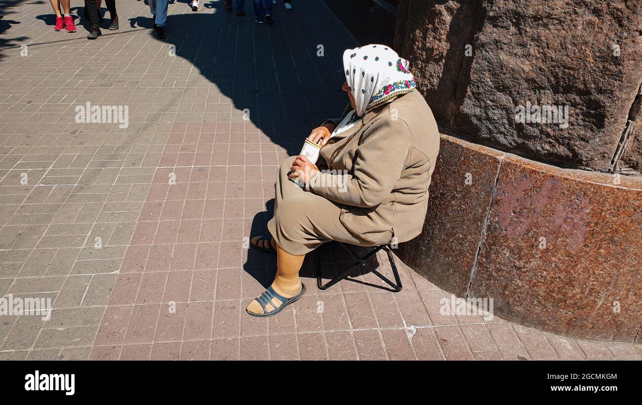 Kiew, Ukraine-1. Mai 2018: Ältere traurige Frau bettelt Geld, während sie auf einem Stuhl in der Kreschatik-Straße in Kiew, Ukraine, sitzt. Stockfoto