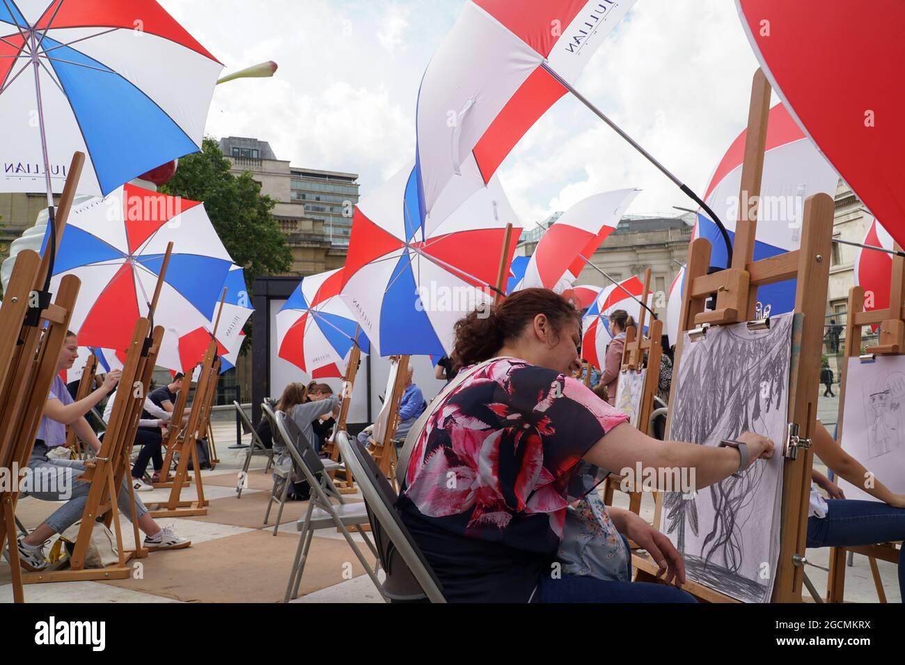 London, Großbritannien, 9. August 2021: Die National Gallery bietet im August im Rahmen des Inside Out Festivals Kunstkurse auf dem Trafalgar Square an. Dreißig Staffeleien wurden aufgestellt -- mit Regenschirmen für das unregelmäßige Sommerwetter -- und Menschen jeden Alters können sich in Sketch on the Square einfinden, um sich bei den Zeichenfähigkeiten zu beraten. Anna Watson/Alamy Live News Stockfoto