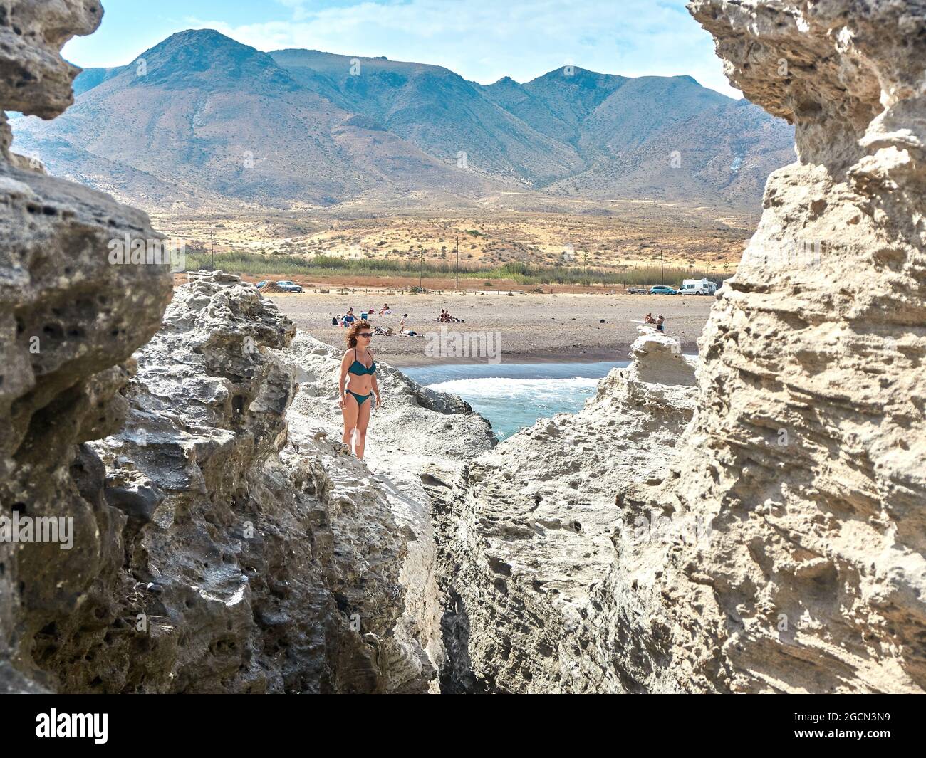 L Los Escullos Strand im Naturpark Cabo de Gata, Nijar.Frau mit Bikini in den Steinen zu Fuß Stockfoto