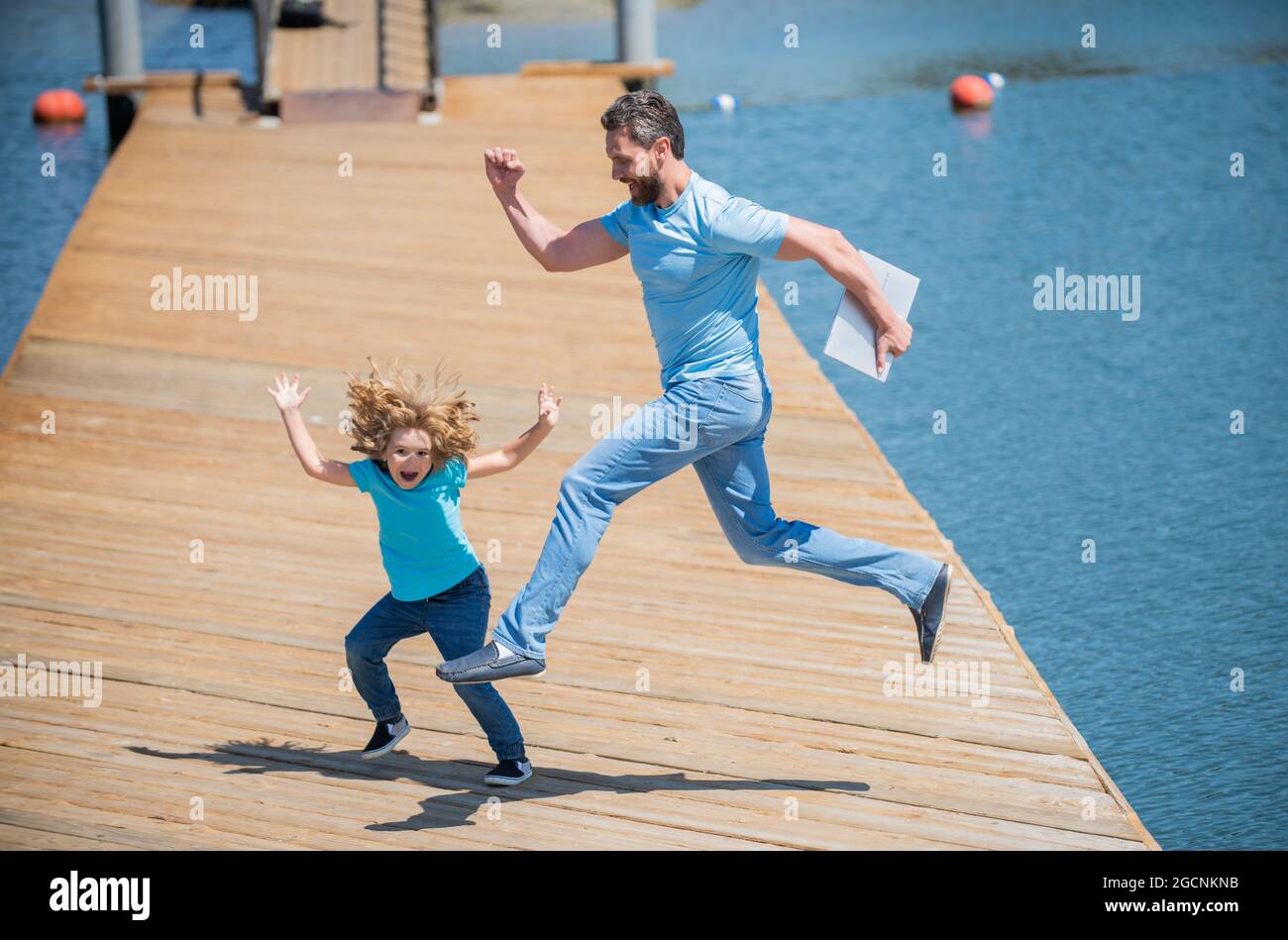 Springen Sie frei. Energischer Vater und Sohn springen auf den Pier. Spaß für die ganze Familie Stockfoto