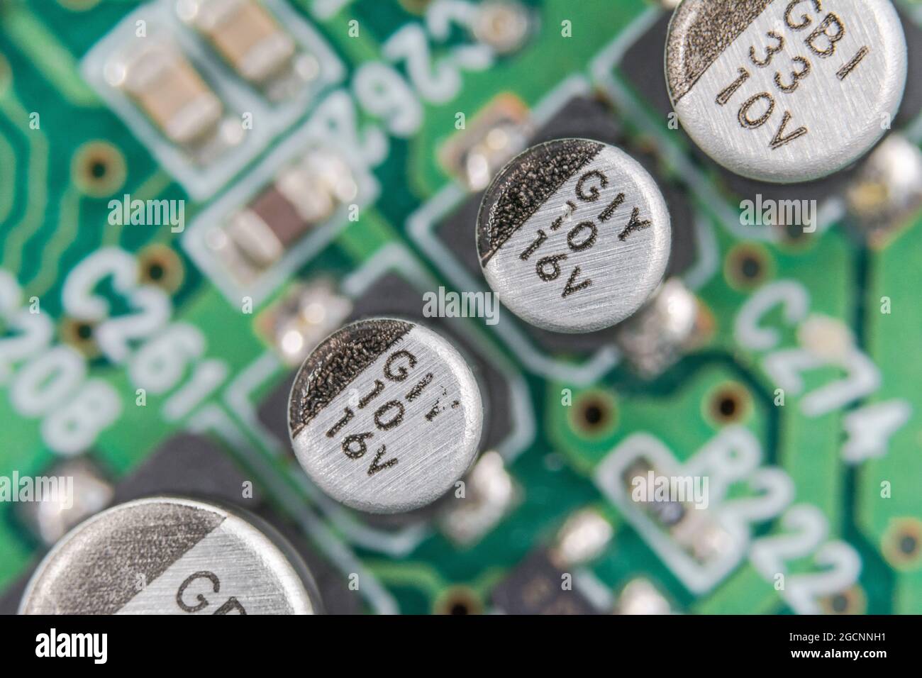 Makrogeschossreihe von SMD V-Chip Hybrid-Aluminium-Elektrolytkondensatoren auf einer leiterplatte, die eine schwarze (Minus-) Polaritätsmarkierung aufweist. Marken nicht identifiziert. Stockfoto