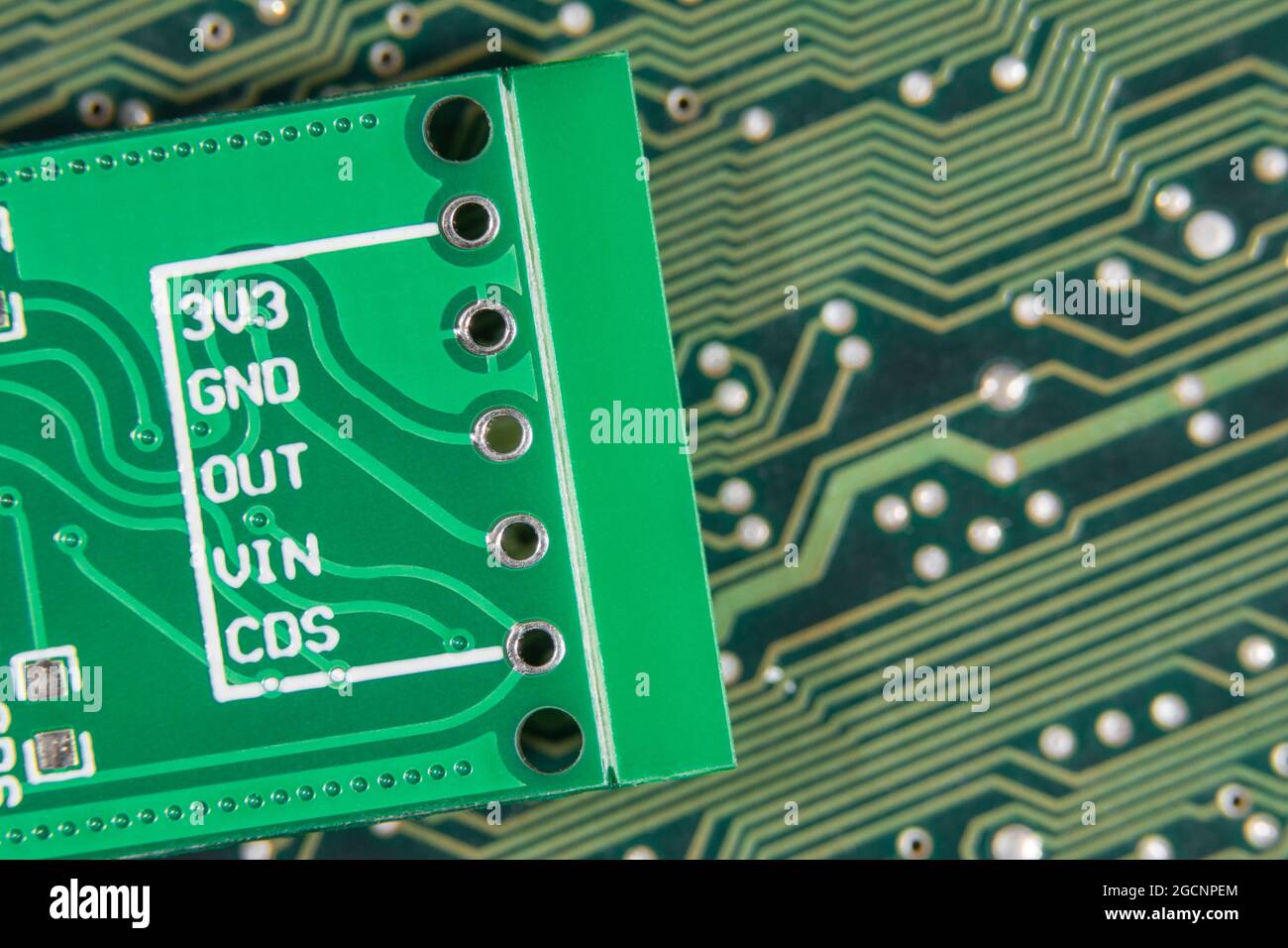 Makroaufnahme der Eingangsbohrungen der leiterplatte für kleine Leiterplatten. Rückseite eines Motion-Sensing-Moduls mit 3 Volt, Masse und anderen pcb-Pinbelegungen. Stockfoto