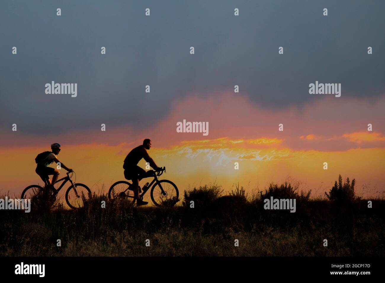 Mann und Frau auf Fahrrädern auf dem Hintergrund eines sehr schönen Sonnenuntergangs Stockfoto