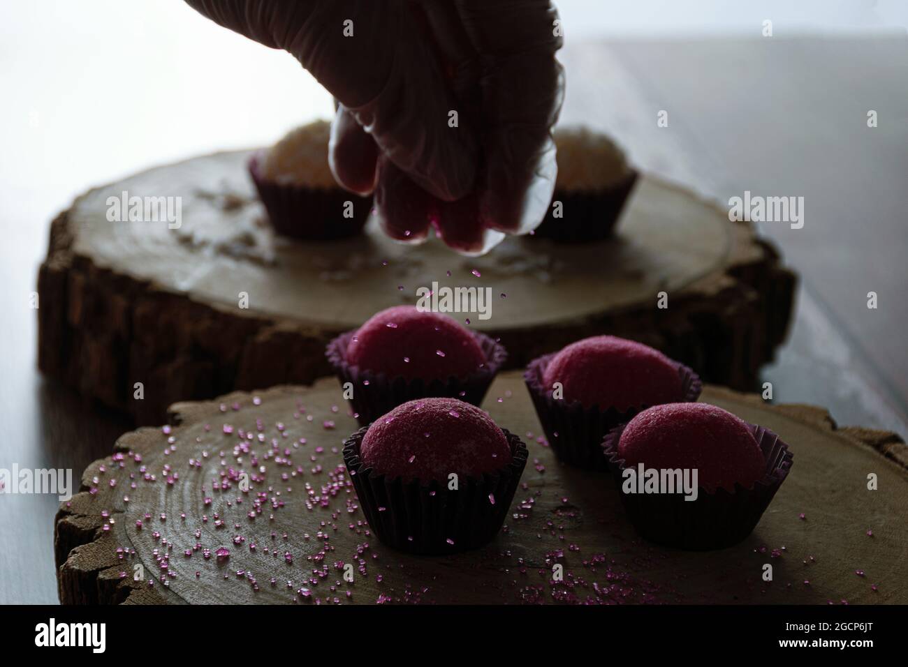 Erdbeere Brigadeiros (Bicho de PE) auf Baumstammschalen, schwaches Foto. Konditor setzen rosa Kristallzucker. Stockfoto
