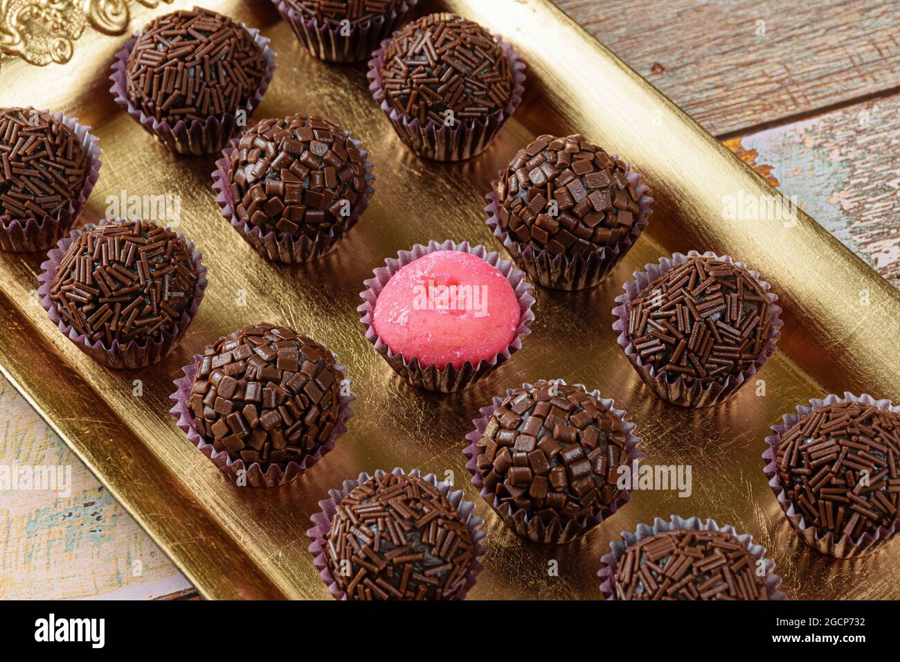 Strawberry Brigadeiro (Bicho de pe), umgeben von traditionellen Brigadeiros (Brigadierern). Auf einem goldenen Tablett aufgereiht Stockfoto