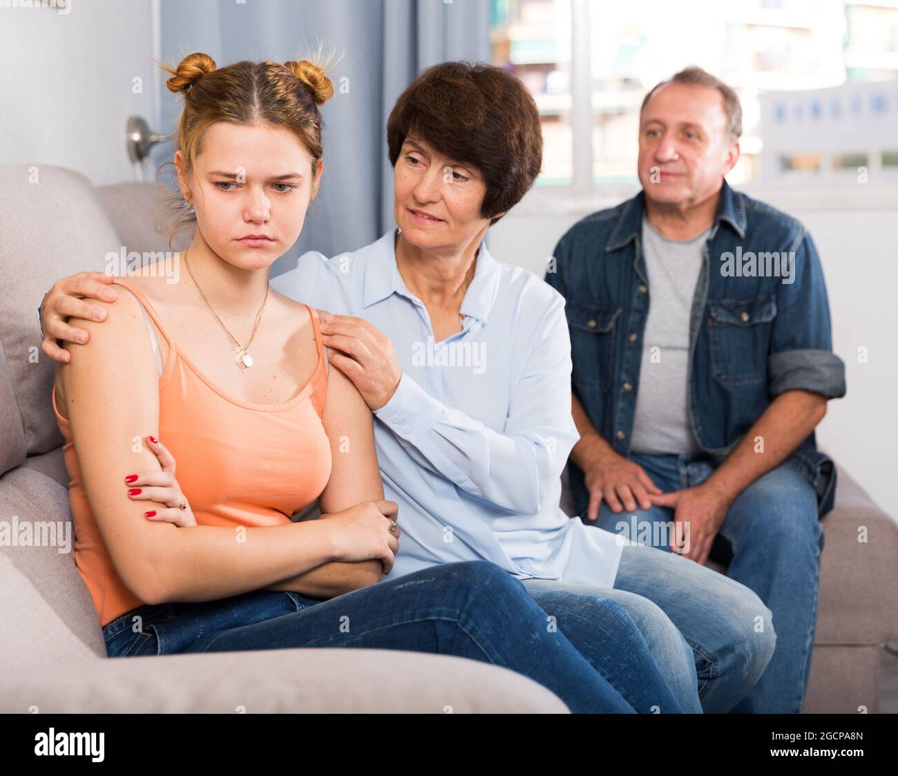 Mama und Papa unterstützen eine traurige Tochter auf dem Sofa Stockfoto