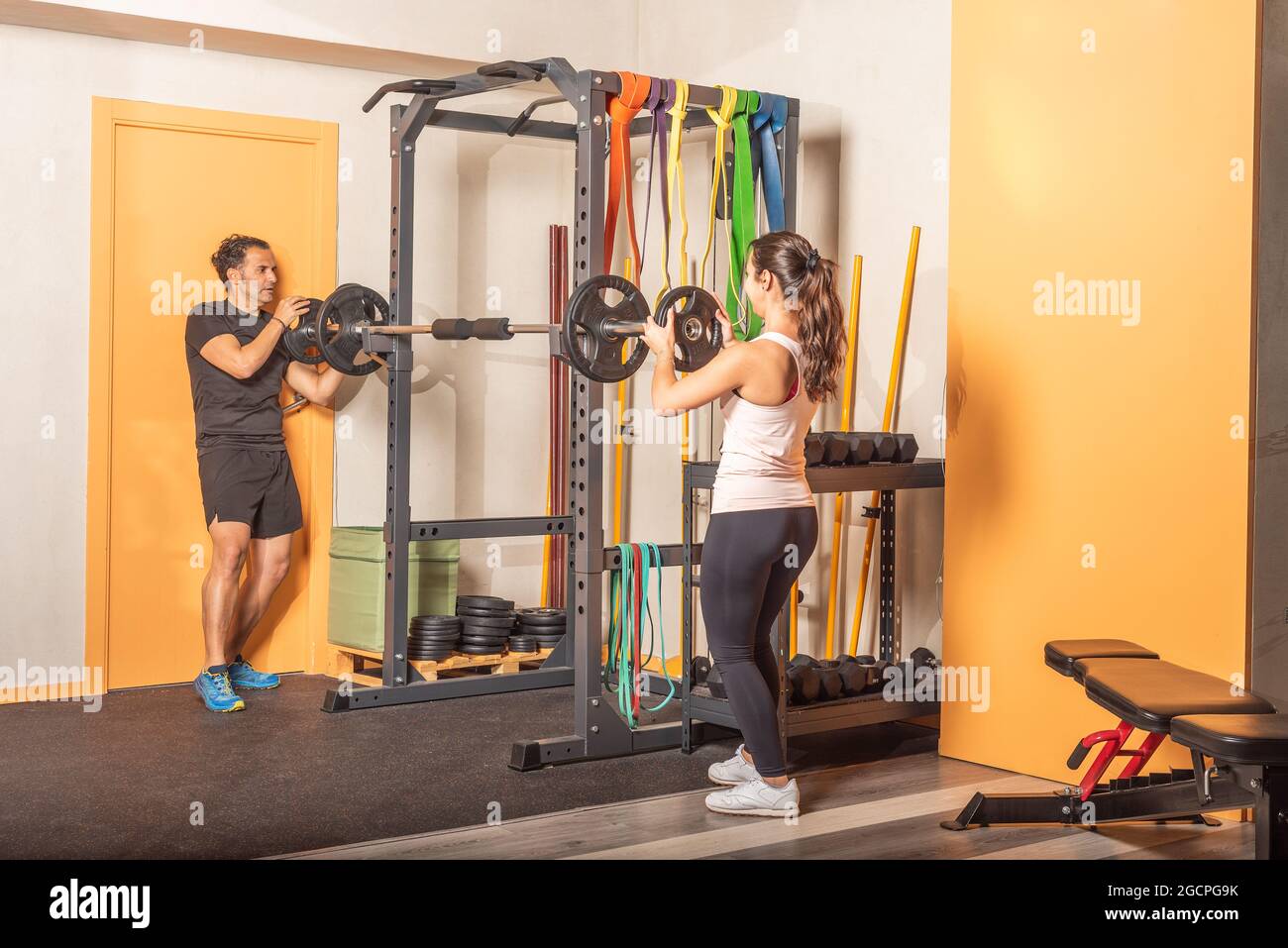 Mann und Frau, die Hantelscheibe an der Bar im Fitnessstudio aufsetzen Stockfoto