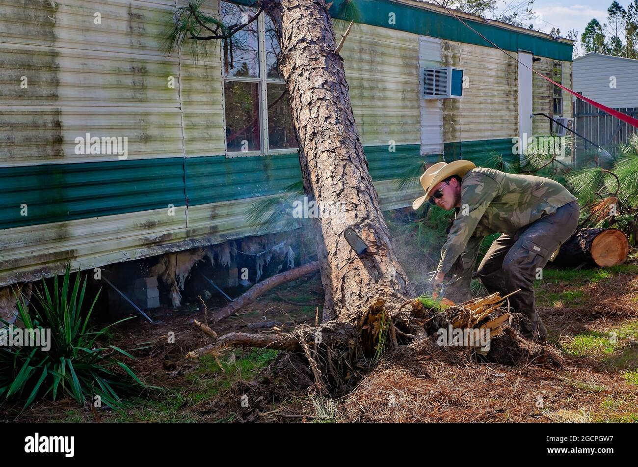 Nach dem Orkil Michael, 18. Oktober 2018, in Marianna, Florida, räumt ein Mann Bäume aus einem Mobilheim im Twin Oaks Mobile Home Park. Stockfoto