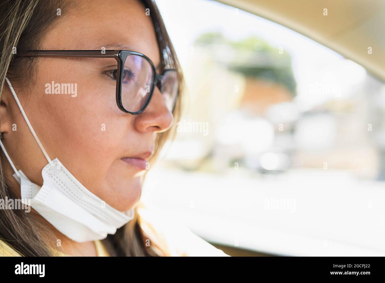 Porträt einer latinerin mit Brille, die mit abgetaschter Maske fährt Stockfoto