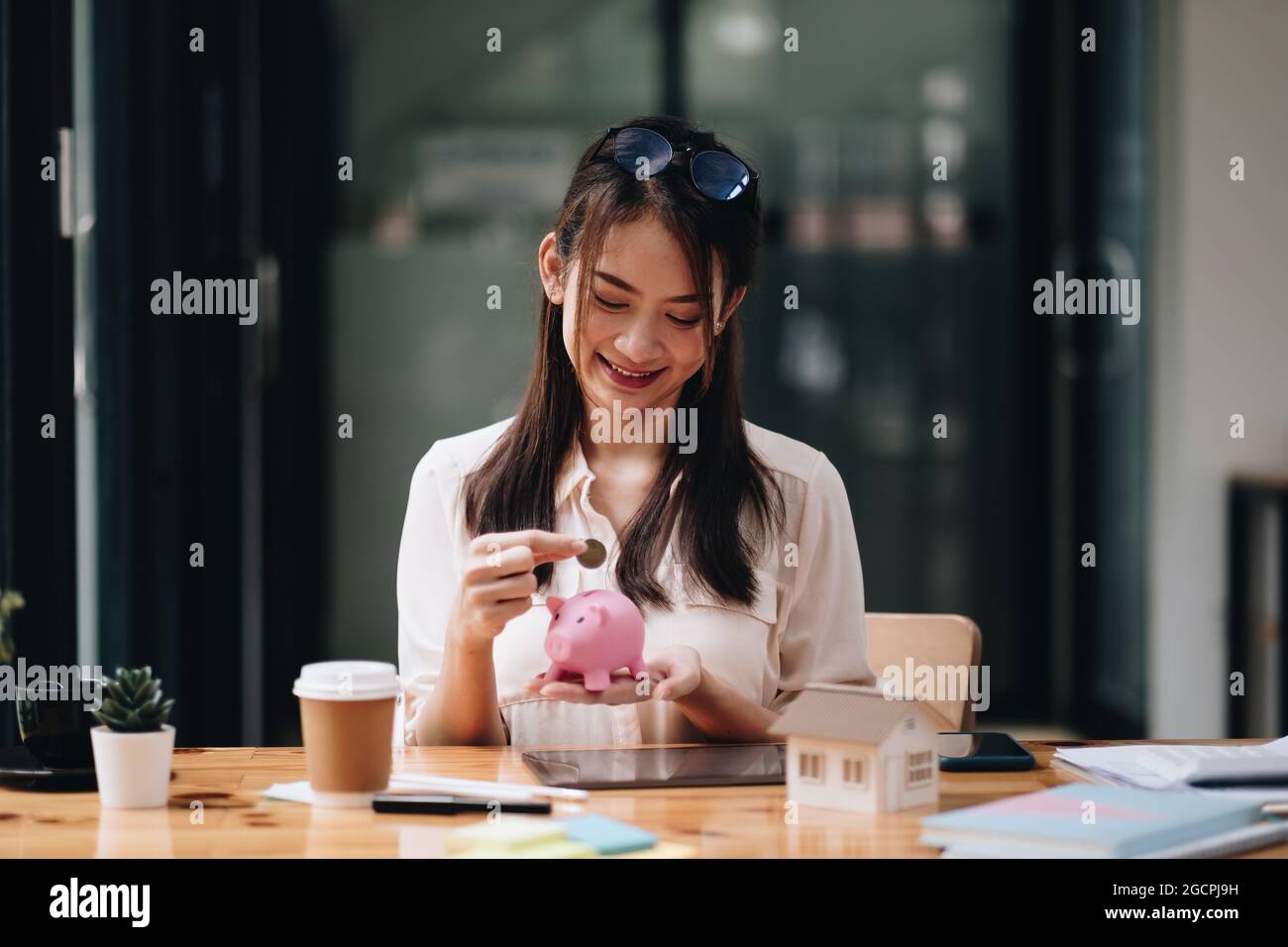 Hypotheken-, Investitions-, Immobilien- und Immobilienkonzept - Nahaufnahme der Frau, die Geld in ein pinkes Sparschwein für Darlehen oder zum Kauf eines neuen Hauses einkauft Stockfoto