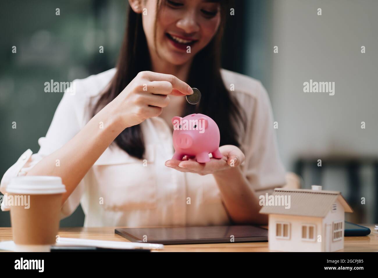 Hypotheken-, Investitions-, Immobilien- und Immobilienkonzept - Nahaufnahme der Frau, die Geld in ein pinkes Sparschwein für Darlehen oder zum Kauf eines neuen Hauses einkauft Stockfoto