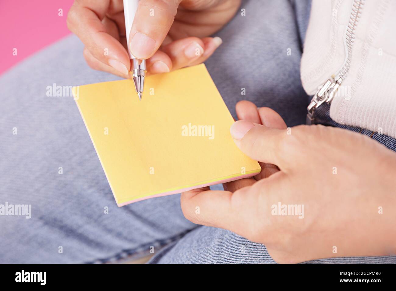 Frau, die Nachricht auf gelbem Notizpapier schreibt.mit weißem Stift auf dem leeren Platz im Notizpapier Stockfoto