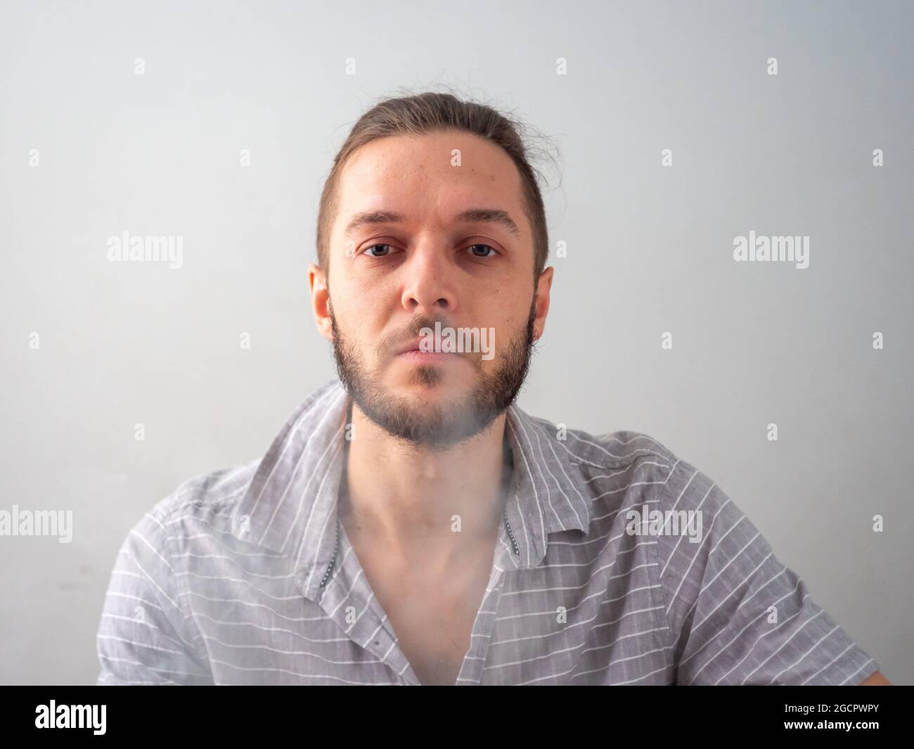 Kaukasischer Mann in grauem Hemd Rauchen legaler Cannabis Joint bläst sich glücklich nieder Stockfoto