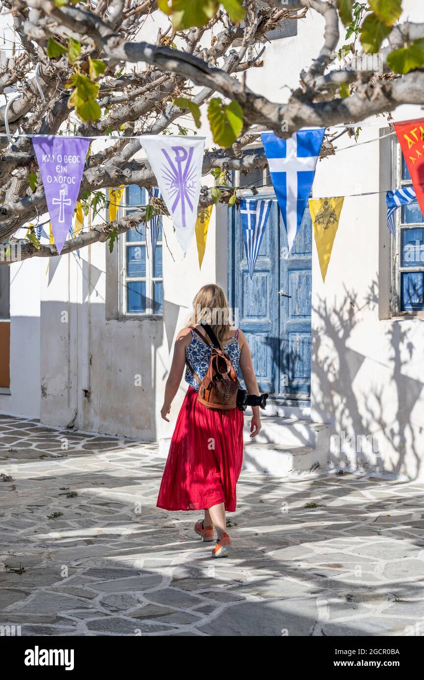 Weiße und blaue Häuser der Kykladen, junge Frau mit rotem Kleid in der Altstadt von Lefkes, Paros, Kykladen, Griechenland Stockfoto