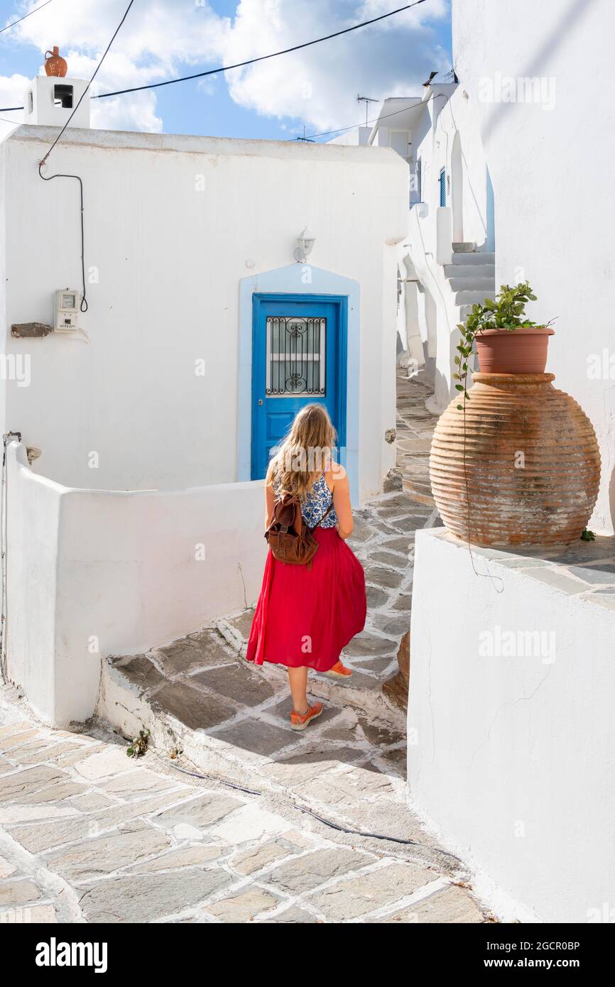 Weiße und blaue Häuser der Kykladen, junge Frau mit rotem Kleid in der Altstadt von Lefkes, Paros, Kykladen, Griechenland Stockfoto