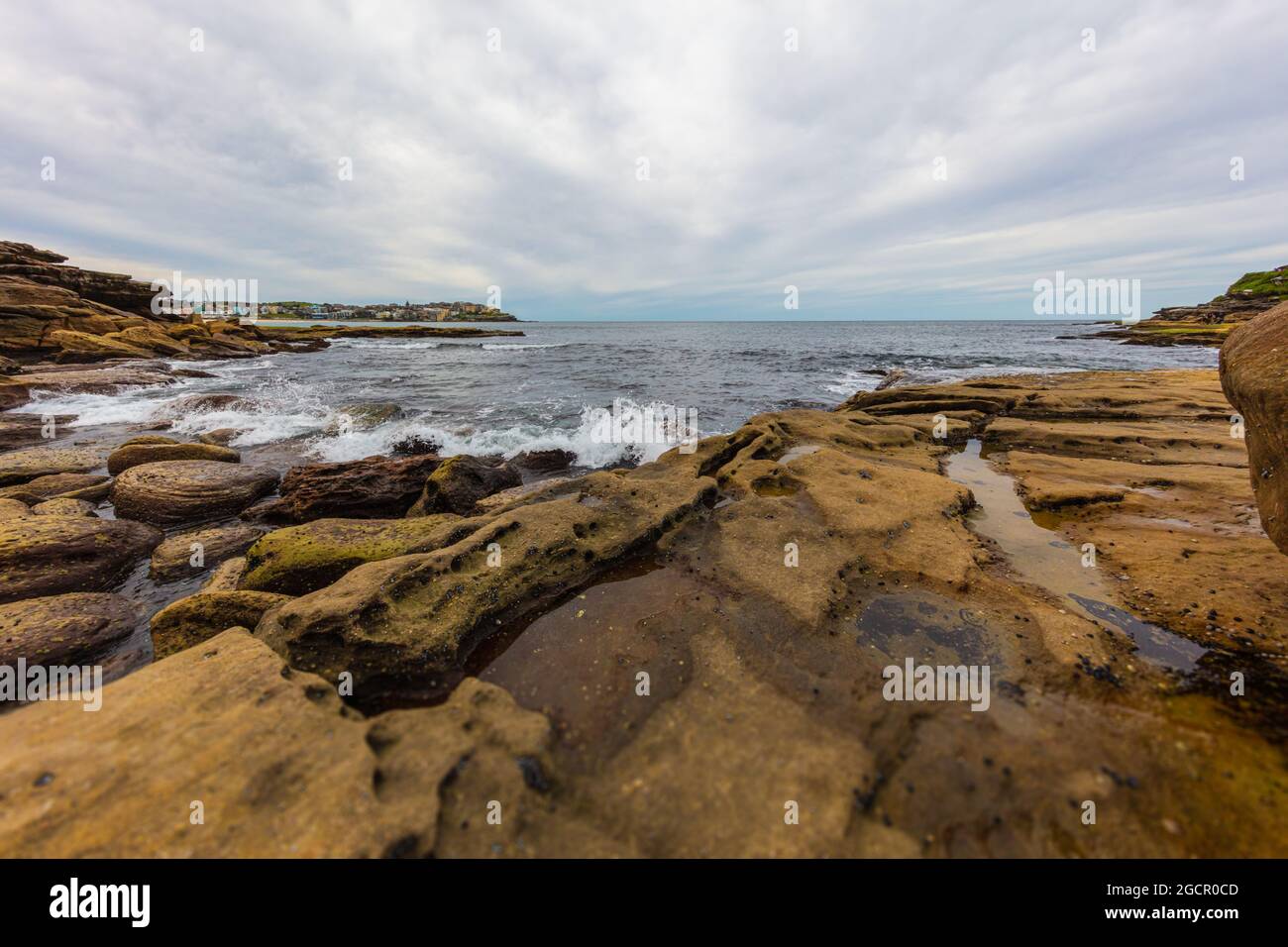 Felsige Küste rund um Bondi Beach, Sydney, Australien. Sonnenuntergang in der Nähe des berühmten Surfer-Strandes. Sonnenuntergang über dem pazifik. Die Sonne spiegelt sich im Smoot Stockfoto