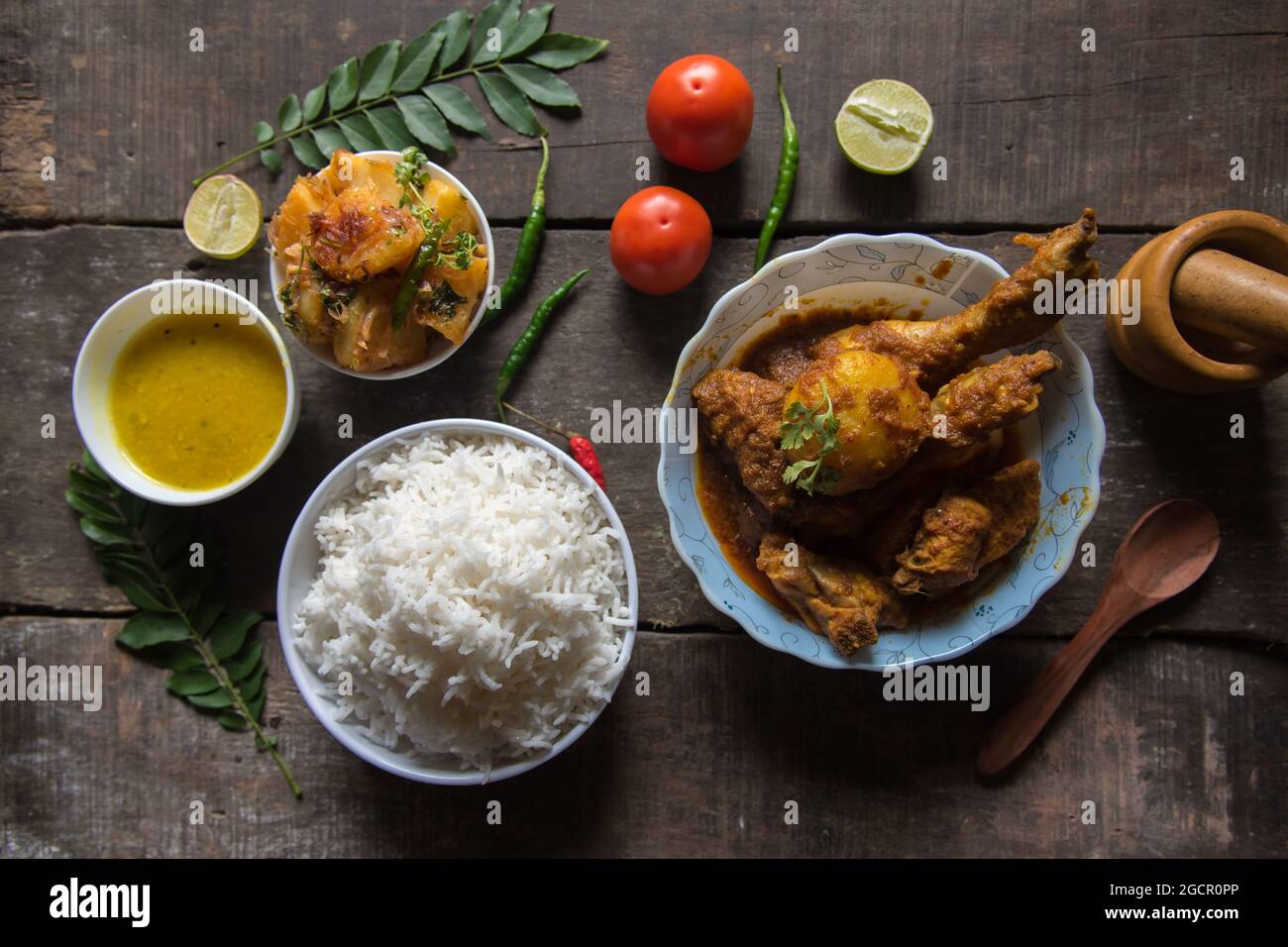 Blick von oben auf indisches Essen oder Mahlzeit mit Kartoffelbraten, Hühnchen-Paprireis, Linsen, Papad und Gewürzen. Nicht vegetarisches Gericht. Stockfoto