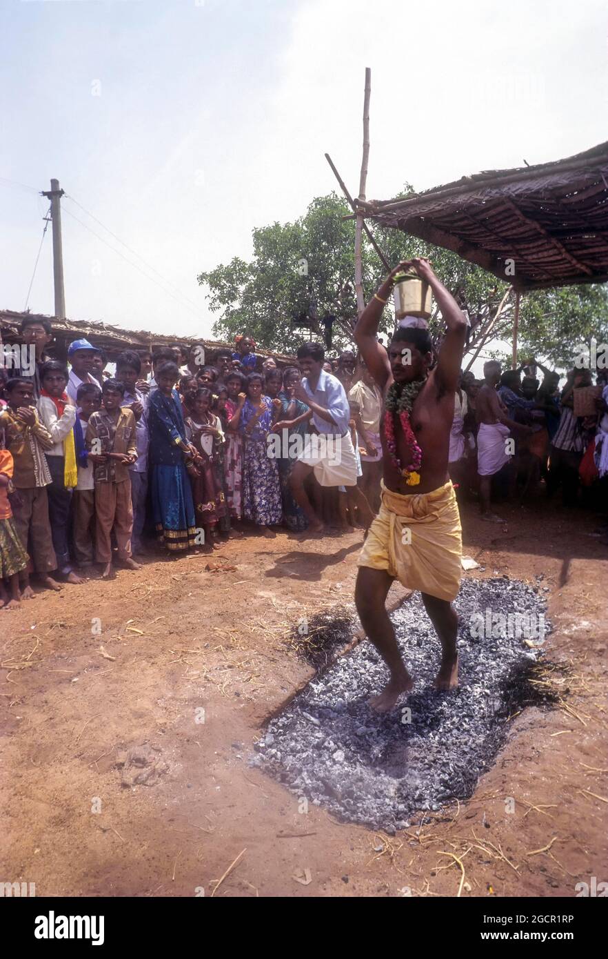 Ein Mann, der Milchtopf auf dem Kopf hält und auf brennender Kohle läuft; Feuer-Wanderfest in Venthanpatti in der Nähe von Pudukottai, Tamil Nadu, Indien Stockfoto