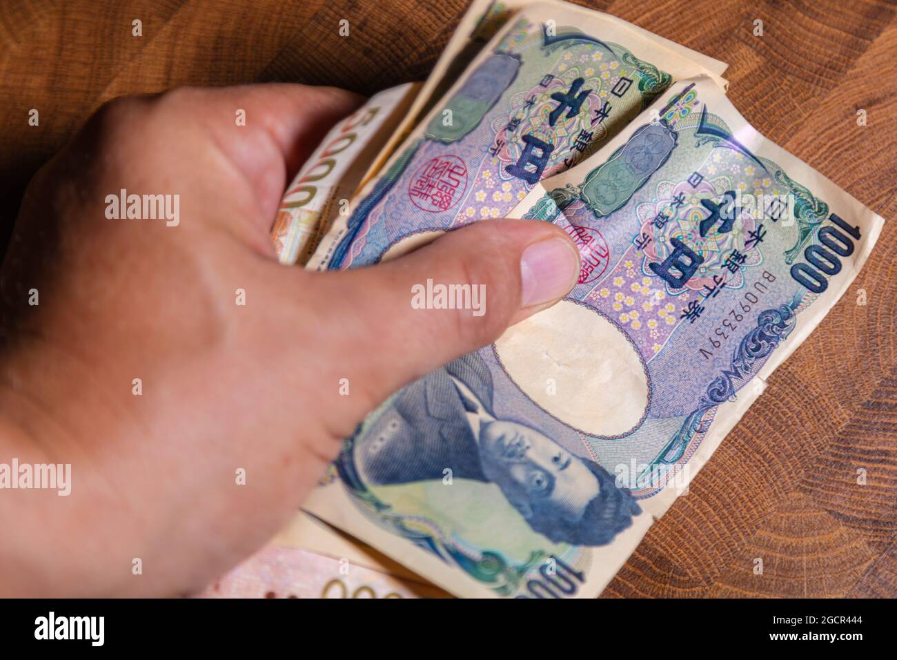 Männliche Hände zeigen japanischen Yen. Yen ist die Währung Japans. Auf der Vorderseite der Banknoten Hideyo Noguchi, Bakteriologe aus dem 20. Jahrhundert Stockfoto