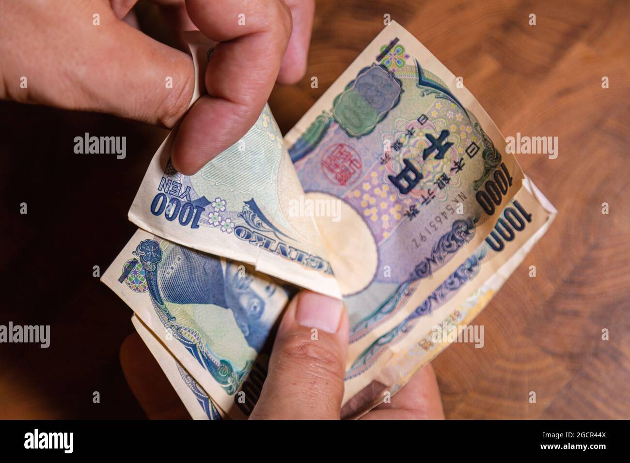 Männliche Hände zeigen japanischen Yen. Yen ist die Währung Japans. Auf der Vorderseite der Banknoten Hideyo Noguchi, Bakteriologe aus dem 20. Jahrhundert Stockfoto