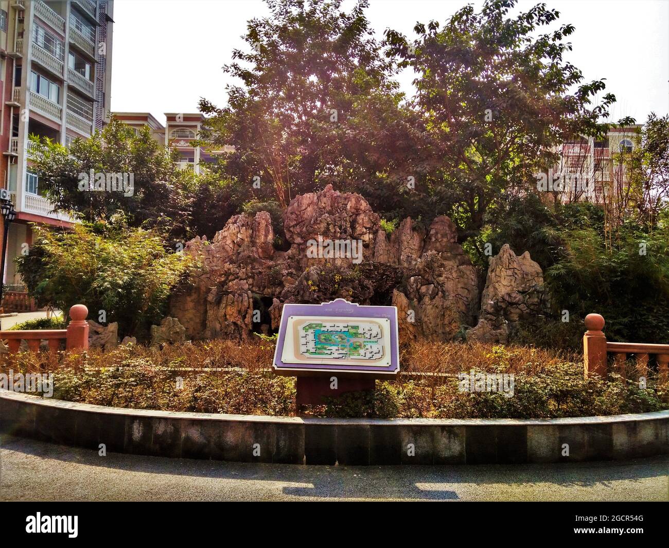 Ein kleiner Gartenbereich mit einem zerklüfteten Felsbrocken, grünen Bäumen, Blumen und einem Kartenschild im Nanxi District Stockfoto