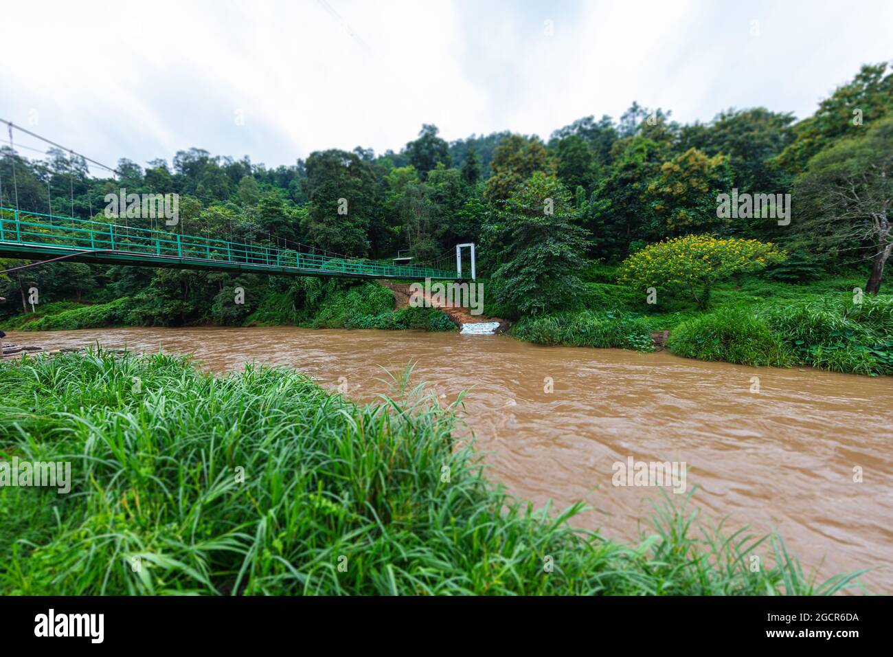 Hängebrücke über den Fluss Mae Taeng in der Nähe von Chiang Mai, Thailand. Der Fluss fließt durch den Regenwald. Bräunliches Wasser im schnell fließenden Wasser Stockfoto
