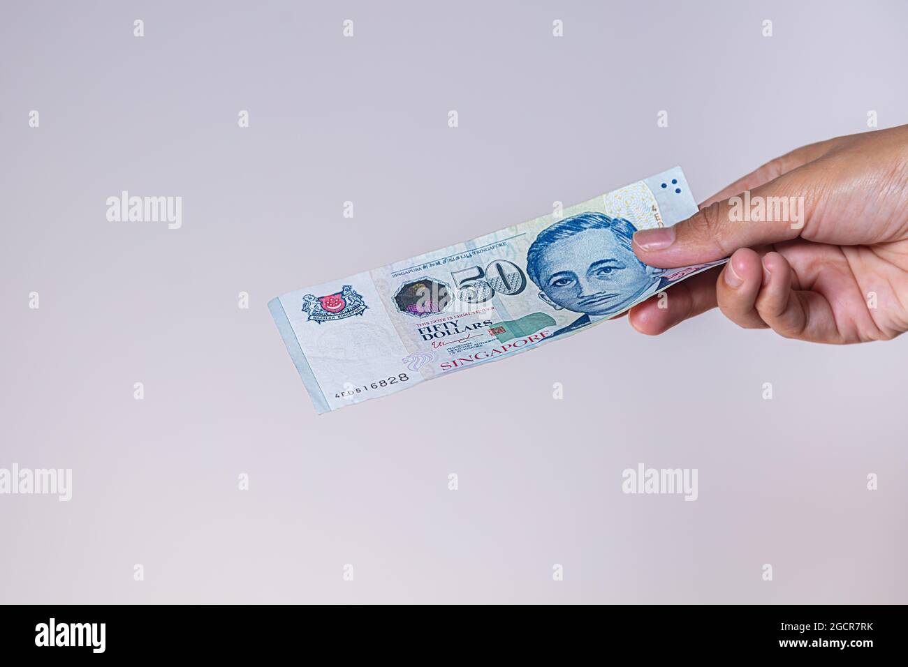 Singapur-Dollar in weiblicher Hand. Die Hände der Frau zeigen singapurische Dollar-Banknoten. Mädchen halten Geld von Singapur. Asiatische Währung. Nahaufnahme Stockfoto
