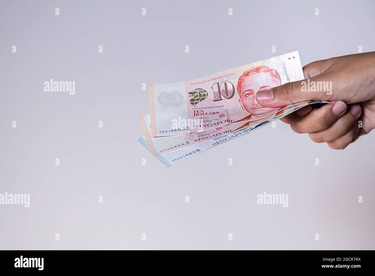 Singapur-Dollar in weiblicher Hand. Die Hände der Frau zeigen singapurische Dollar-Banknoten. Mädchen halten Geld von Singapur. Asiatische Währung. Nahaufnahme Stockfoto
