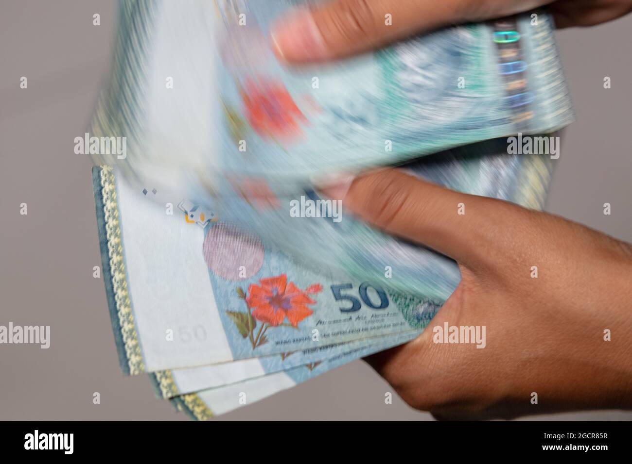 Weibliche Hände zählen malaysischen Ringgit. 50 Ringgit ist nach dem einen Ringgit-Schein die höchste verwendete Banknote in Malaysia. Die Hände der Frau zählen das Neueste Stockfoto
