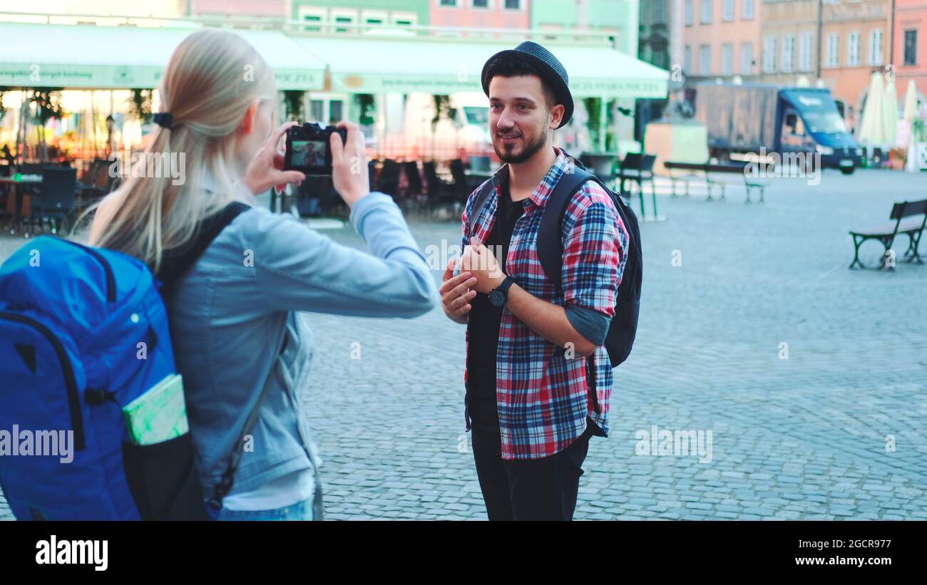 Ein paar Touristen machen Fotos mit der Fotokamera auf dem historischen Marktplatz. Mann posiert und Frau fotografiert. Stockfoto