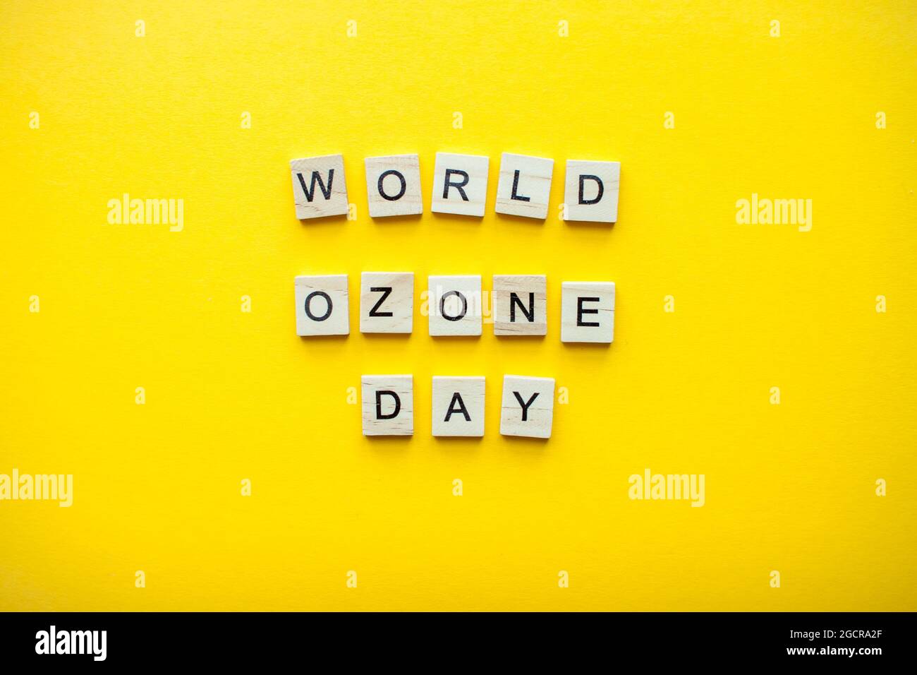 Die Inschrift Welt Ozon Tag aus Holzblöcken auf einem hellgelben Hintergrund Stockfoto