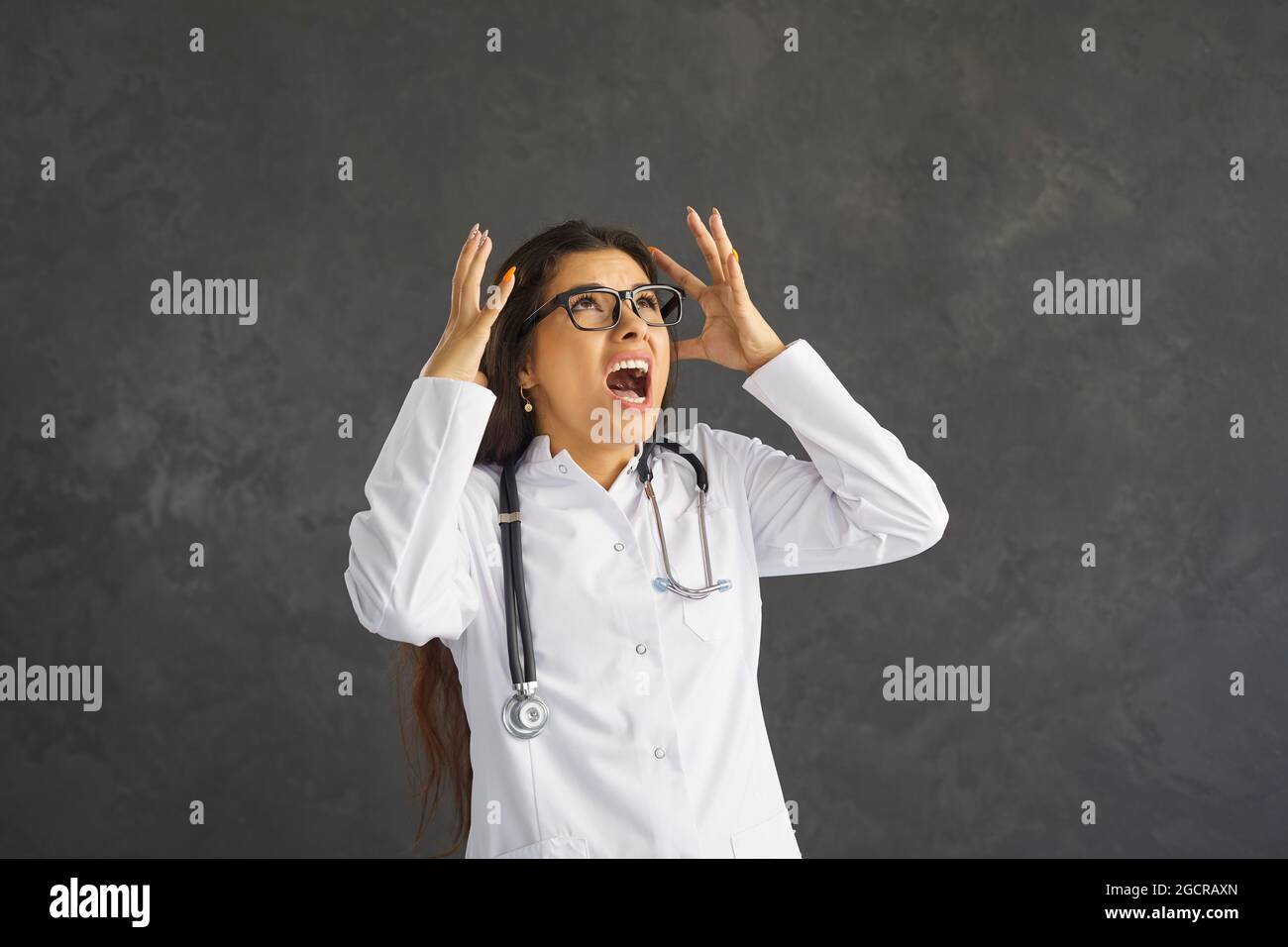 Wütend gestresste junge Ärztin, die müde von ihrem schwierigen Job und ihren Arbeitproblemen schrie Stockfoto