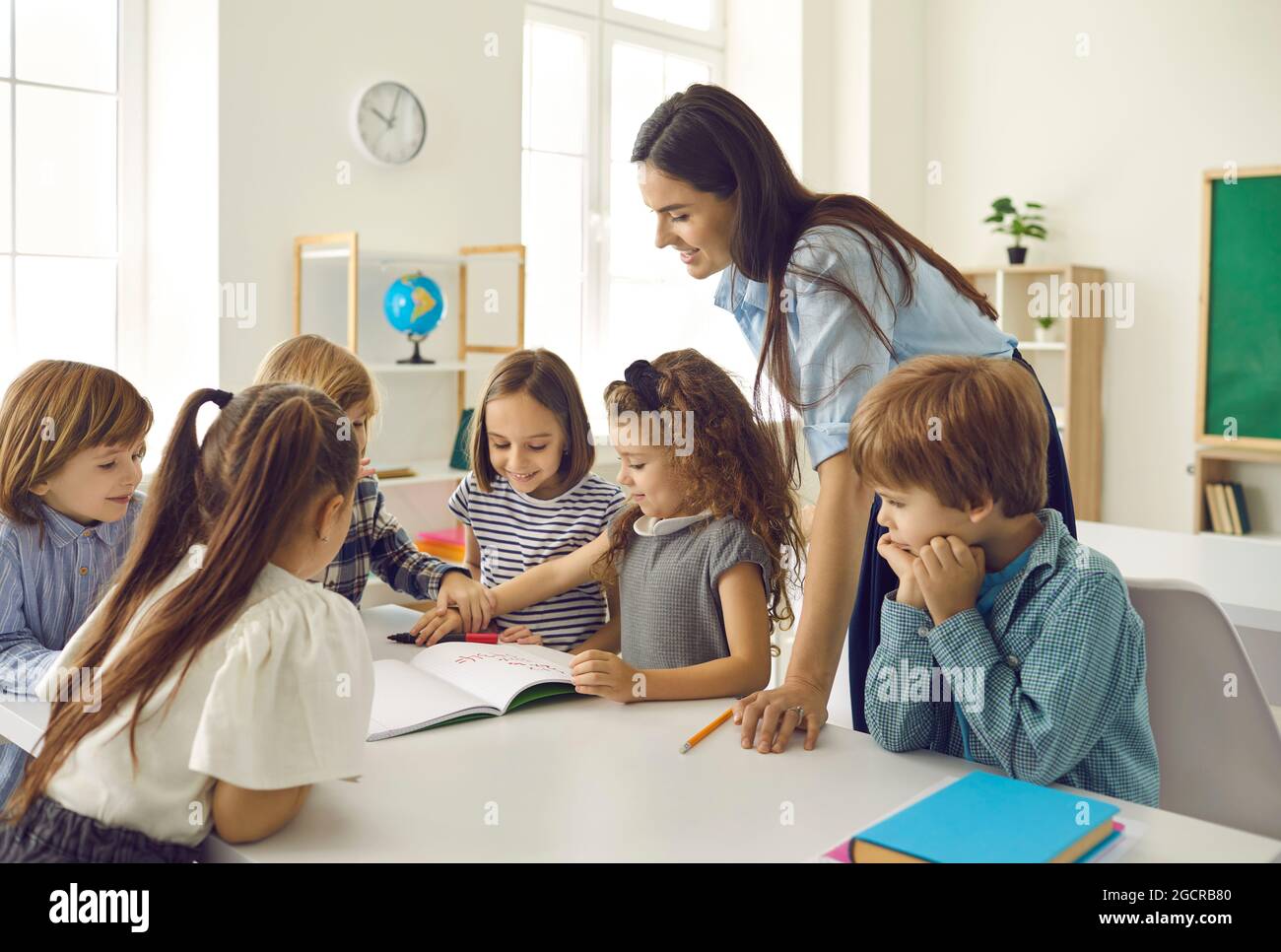 Eine Gruppe glücklicher Schulkinder und deren Lehrer, die eine Klasse im Klassenzimmer haben Stockfoto