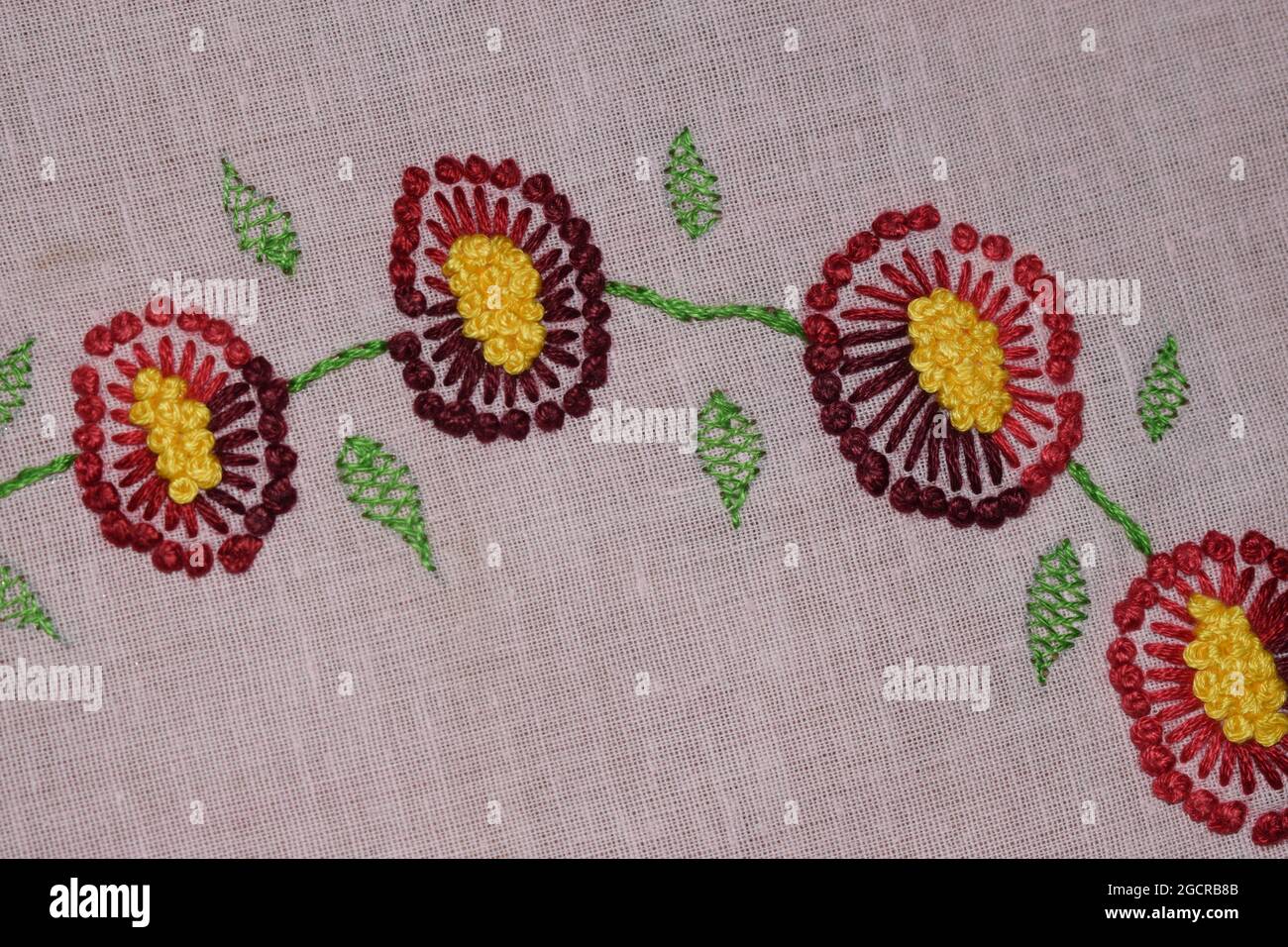 Stechblume, Handstickerei-Design aus Stechblumen und kurzen Fischgrätstichblättern auf dem rosa Stoff, Stoffstickerei-Kunst Stockfoto