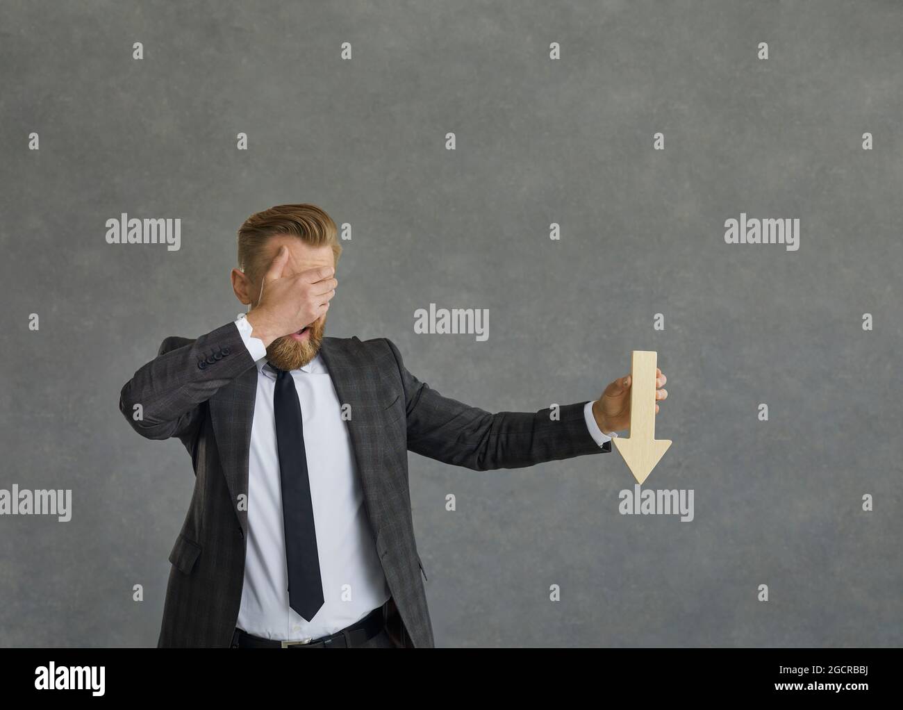 Schockiert verwirrt Geschäftsmann Augen mit Hand zeigt Pfeil nach unten Stockfoto