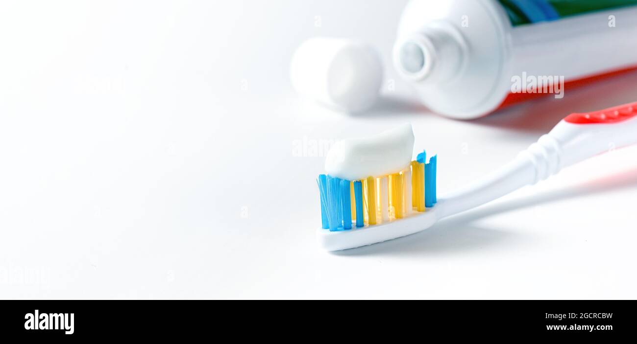 Zahnbürste mit weißer Zahnpasta und Tube Zahnpasta auf weißem Hintergrund Stockfoto