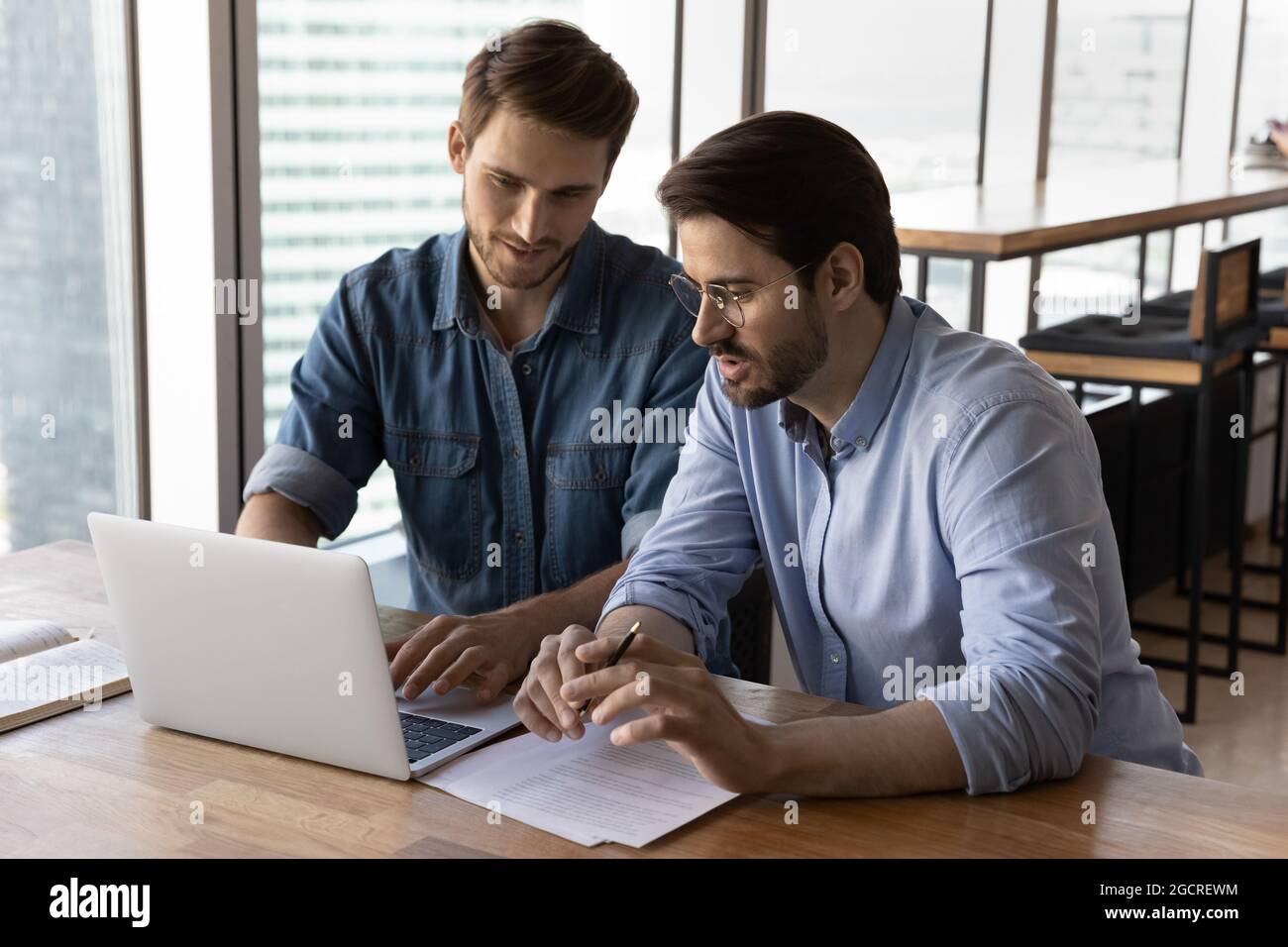 Geschäftsleute diskutieren Projekt am Laptop, Blick auf den Bildschirm, reden Stockfoto