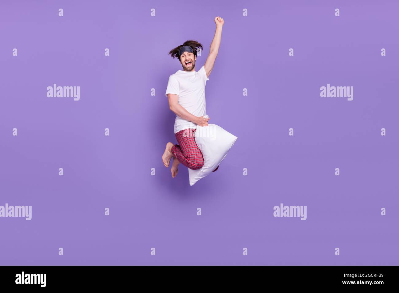 In voller Größe Porträt von sorglosen überglücklich Person fliegen auf Kissen heben Faust isoliert auf violettem Hintergrund Stockfoto