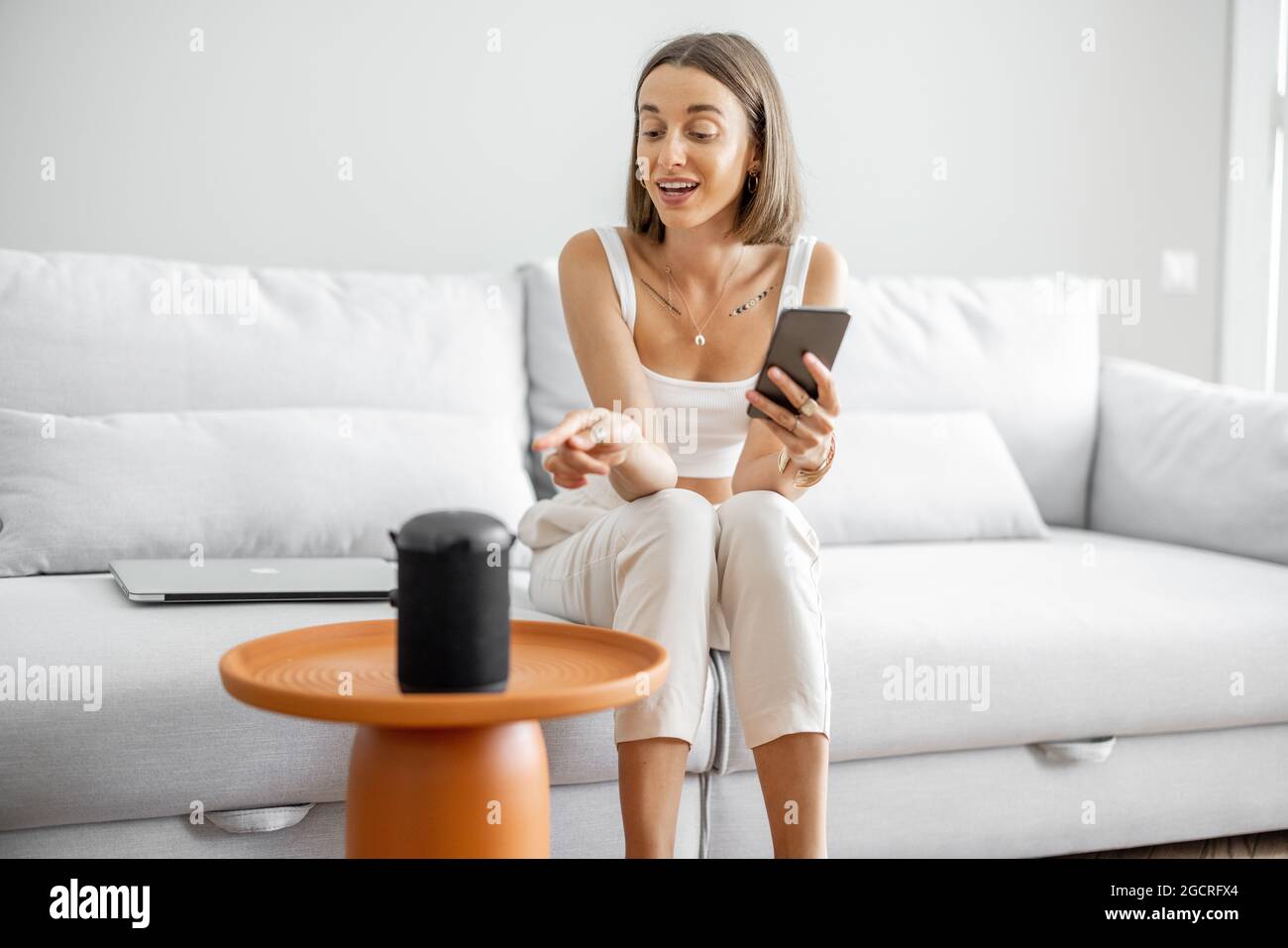 Frau, die Heimgeräte mit Sprachbefehlen verwaltet Stockfoto