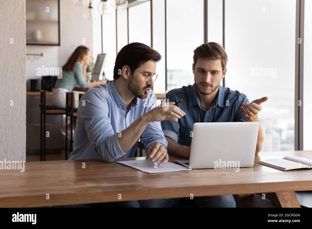 Büroangestellte diskutieren am Laptop über das Projekt und teilen Ideen Stockfoto