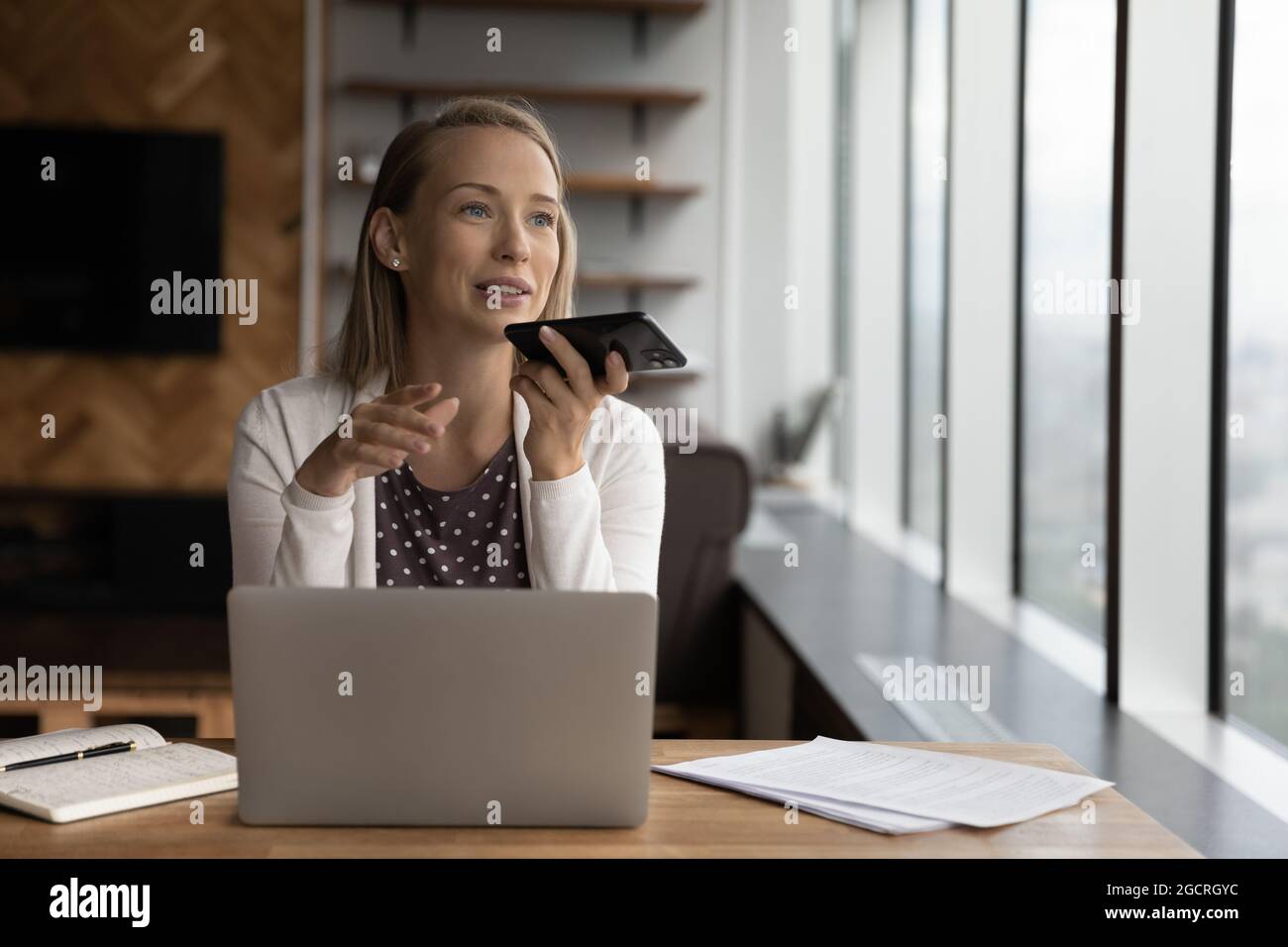 Glückliche Geschäftsfrau, die Audionachrichten auf dem Handy aufzeichnet Stockfoto