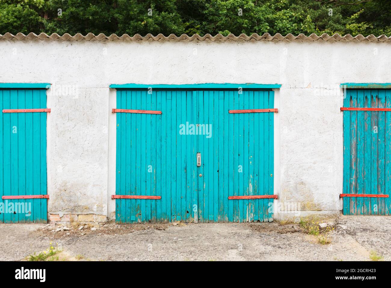 Verwitterte, leuchtend türkisfarbene Garagentore in einem Hinterhof Stockfoto