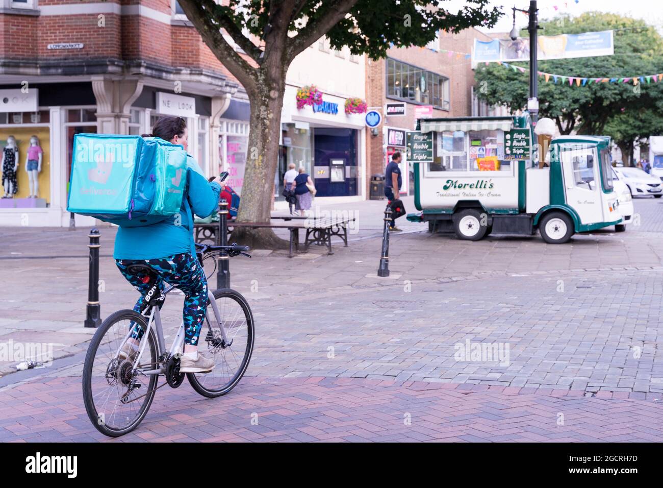 Deliveroo Rider überprüft das mobile Gerät auf die Richtung im Stadtzentrum von Canterbury, Kent England Stockfoto