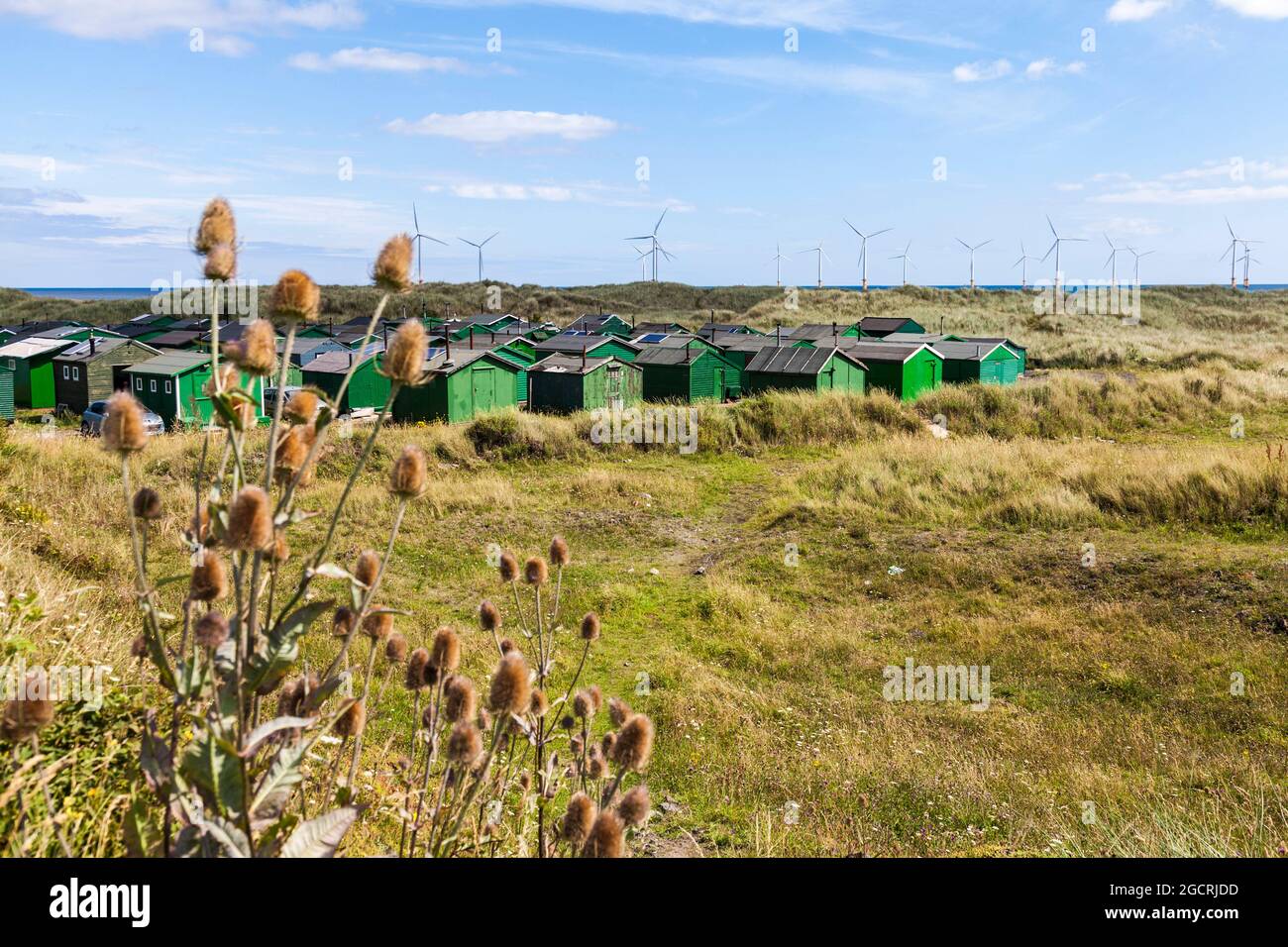 Die fishermens Hütten am South Gare, Redcar, England, Großbritannien mit Offshore- Windenergieanlagen im Hintergrund Stockfoto