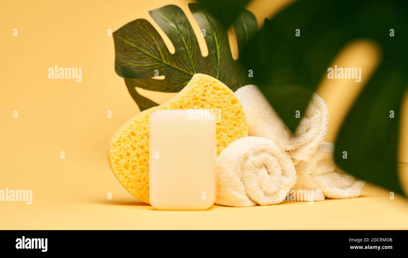 Bad- und Spa-Accessoires. Seife, Handtücher und Körperschwamm auf gelbem Hintergrund Stockfoto