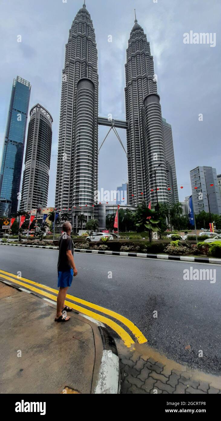 KUALA LUMPUR, MALAYSIA - 29. Jan 2020: Ein Mann, der vor den Petronas Twin Towers steht, einem Zwillingskomplex in Kuala Lumpur Stockfoto