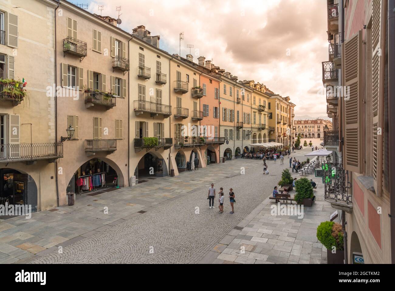 CUNEO, PIEMONT, ITALIEN - 2. AUGUST 2021: Via Roma bei Sonnenuntergang mit historischen bunten Gebäuden mit Arkaden (portici von Cuneo), Galimberti-Platz im Stockfoto